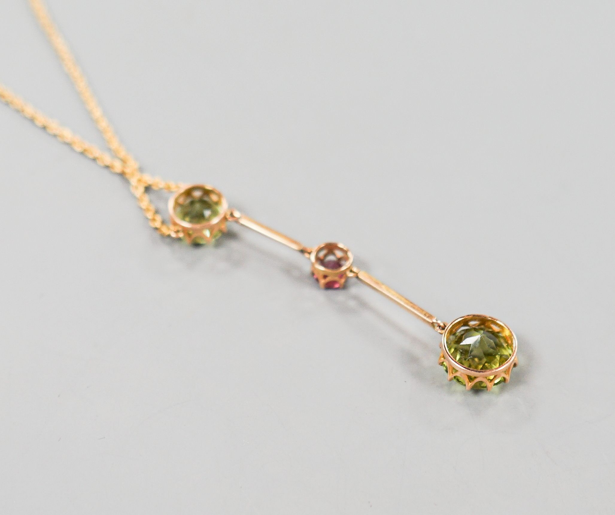 A 20th century yellow metal, two stone peridot and single stone pink tourmaline? set drop line pendant necklace, 51cm, gross 5.5 grams.